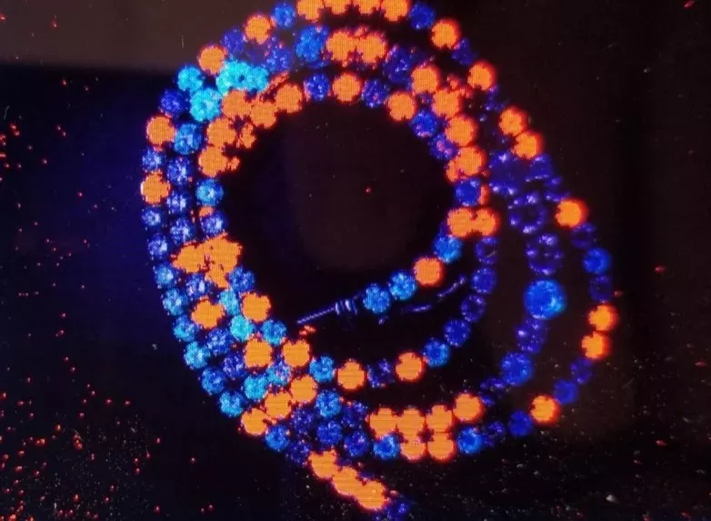 A damond necklace in a Lee Read lab grown diamond tester showing lab grown diamonds in orange and natural diamonds in blue. 